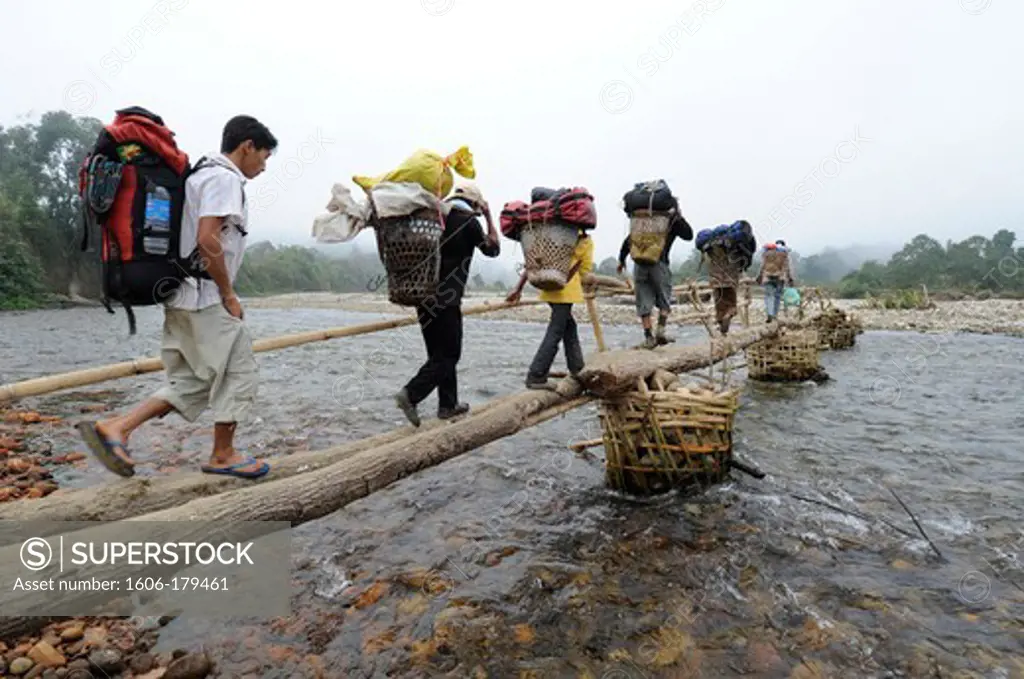 Burma,Myanmar, Putao area, a group of porters is crossing a river on a bamboo bridge