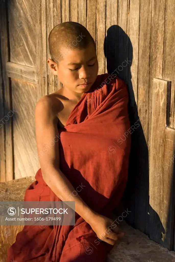 Myanmar Burma BAGO a young monk in his red toga is lit by a light ray