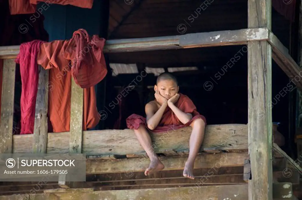 Burma myanmar BAGO a young monk sitting on a wooden terrass is dreaming