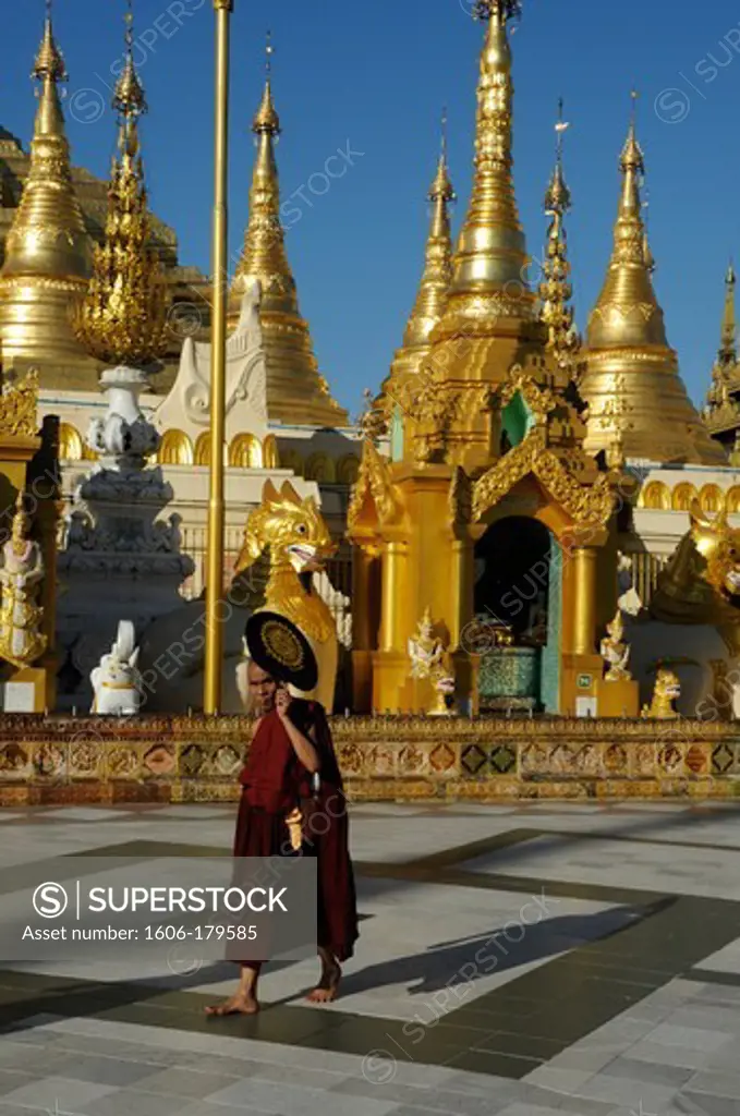 Myanmar Burma Yangon SHWEDAGON pagoda a monk is walking and holding a bamboo fan to protect his face from the sun