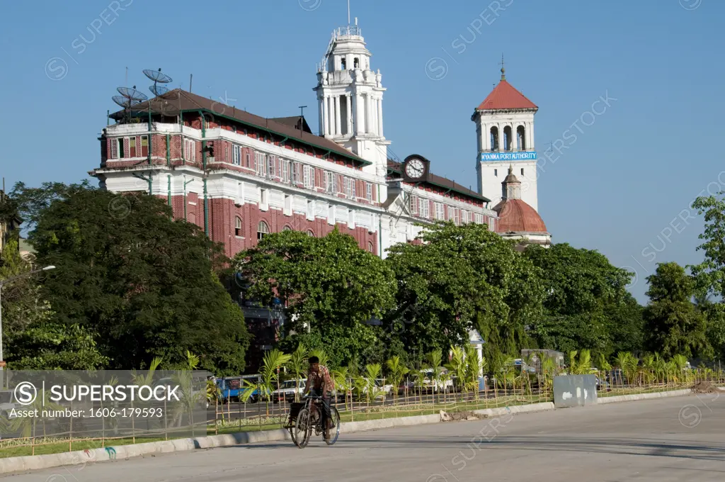 Myanmar Burma Yangon STRAND STREET a man riding a rickshaw is passing in front of a building from the english period
