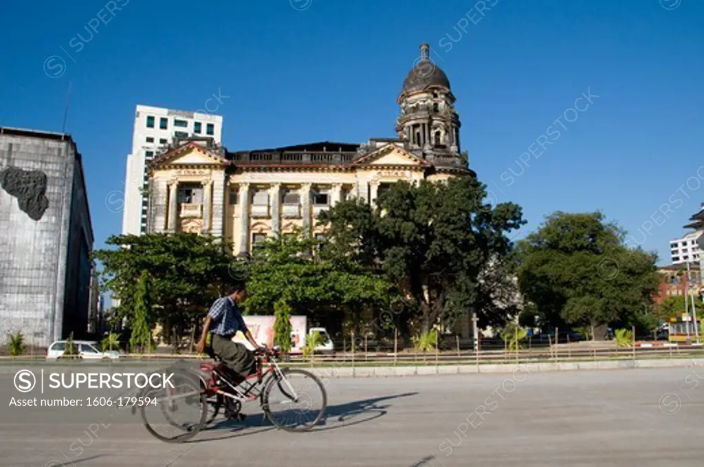 Myanmar Burma Yangon STRAND STREET a man riding a rickshaw is passing in front of a building from the english period