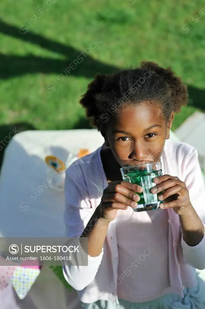 Close up on a young  girl drinking a glass of mint syrup in a garden Model release : oui, Property release : oui
