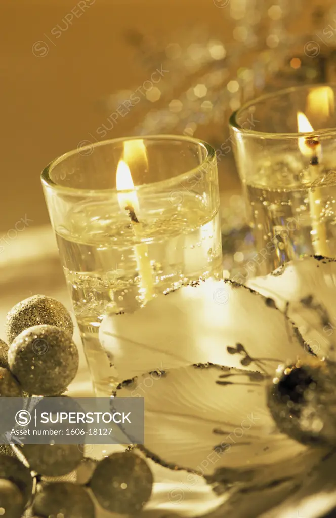 Composition, bougies allumées, boules argentées, pétales de fleur en tissu