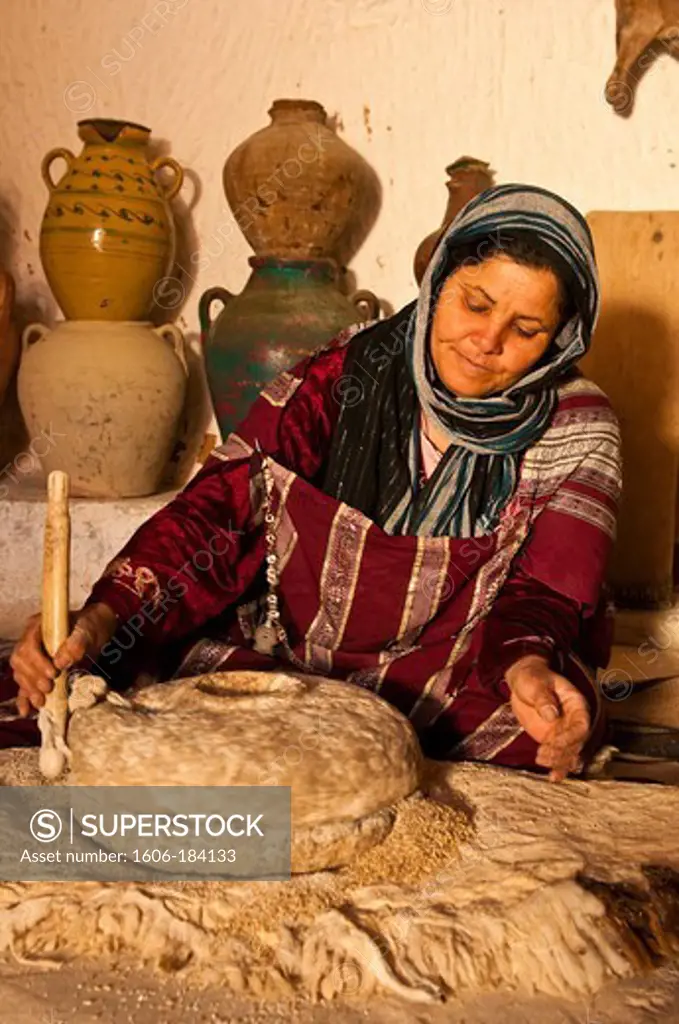 North Africa, Tunisia, Gabes province, cave-dwelling berbere village, Matmata, Ksar Ben Aïssa, the owner Jalila Ben Slimane grinds john barleycorn in her kitchen