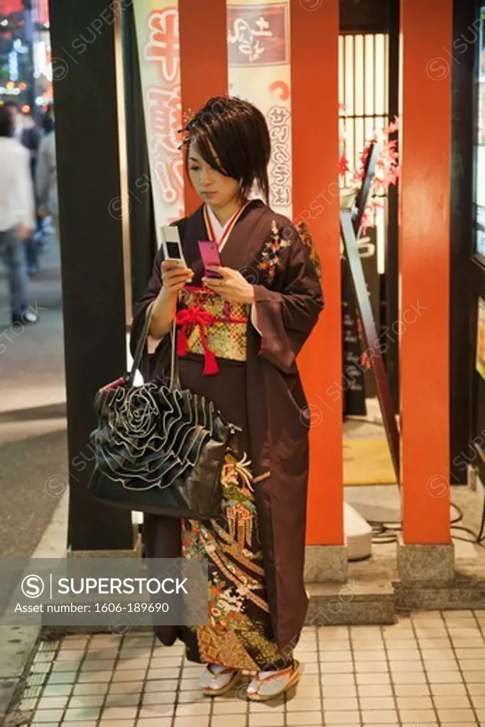 Japan, Tokyo, Roppongi, Young Girl in Kimono Holding Two Mobile Phones