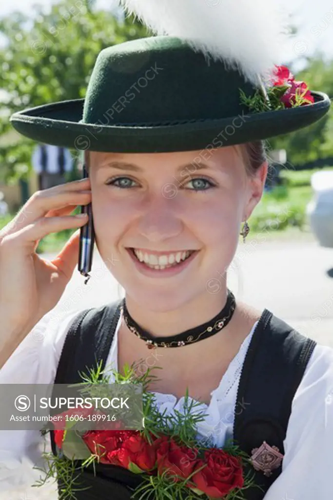Germany, Bavaria, Burghausen, Folklore Festival, Girl in Traditional Baverian Costume with Mobile Phone
