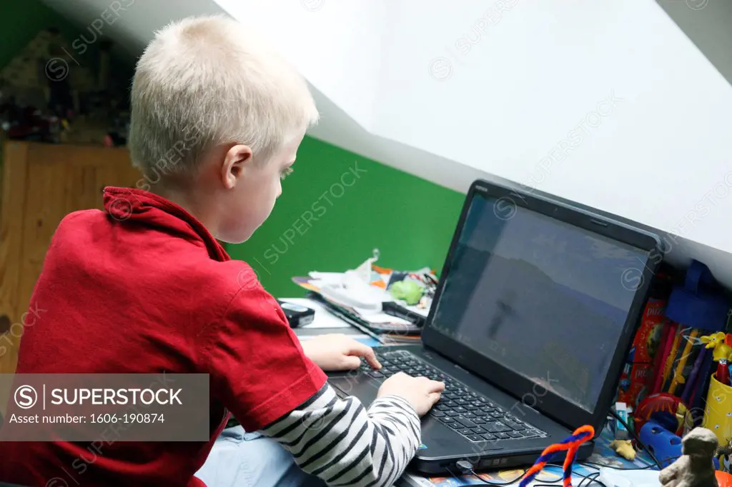 young boy working on computer in his bedroom