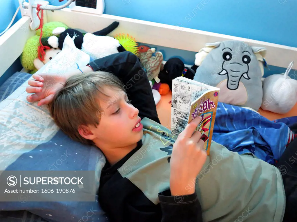 young teenager reading a book on his bed