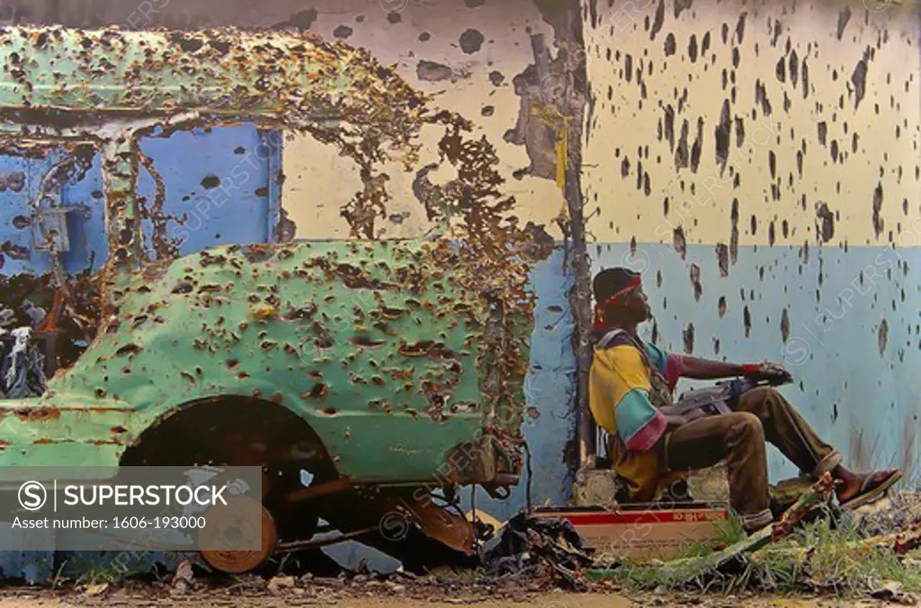 Child Soldier Behind A Bullet-Ridden Car
