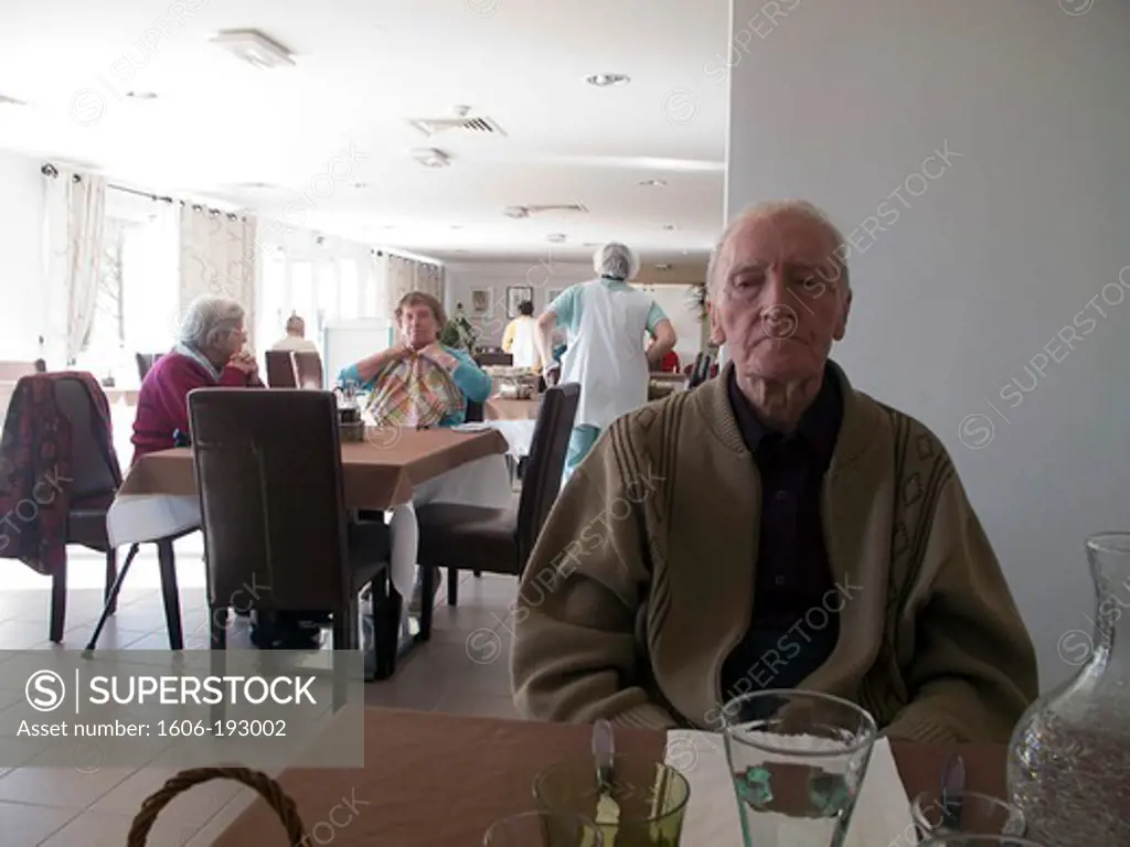 Old Man Sitting At A Table In A Retirement Home Dining Room