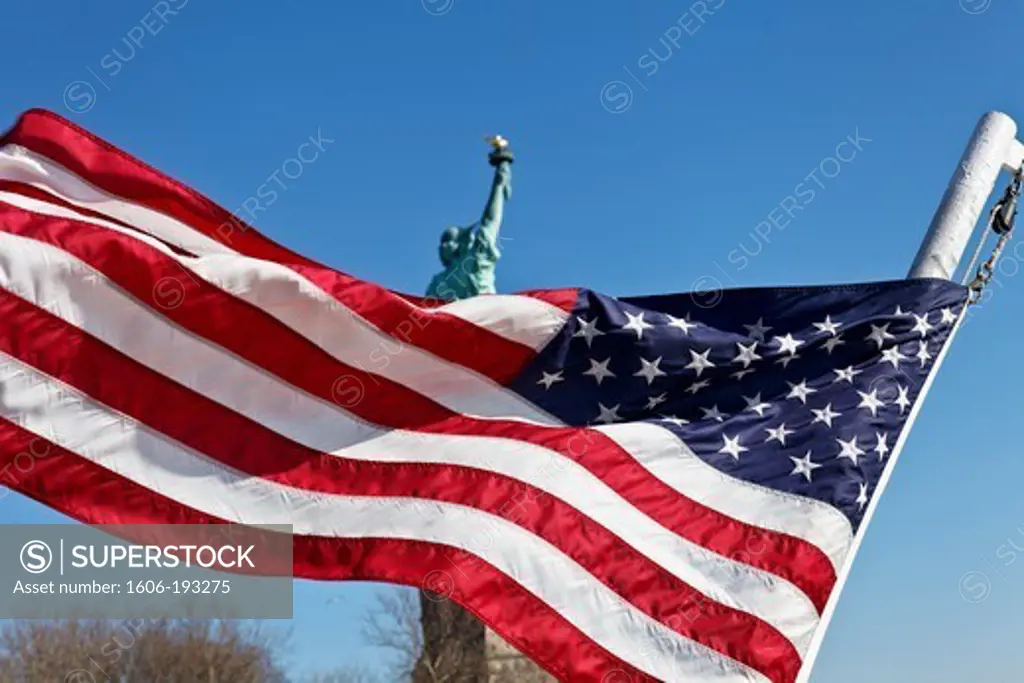 USA, New York City, American Flag Floating With The Statue Of Liberty In The Background