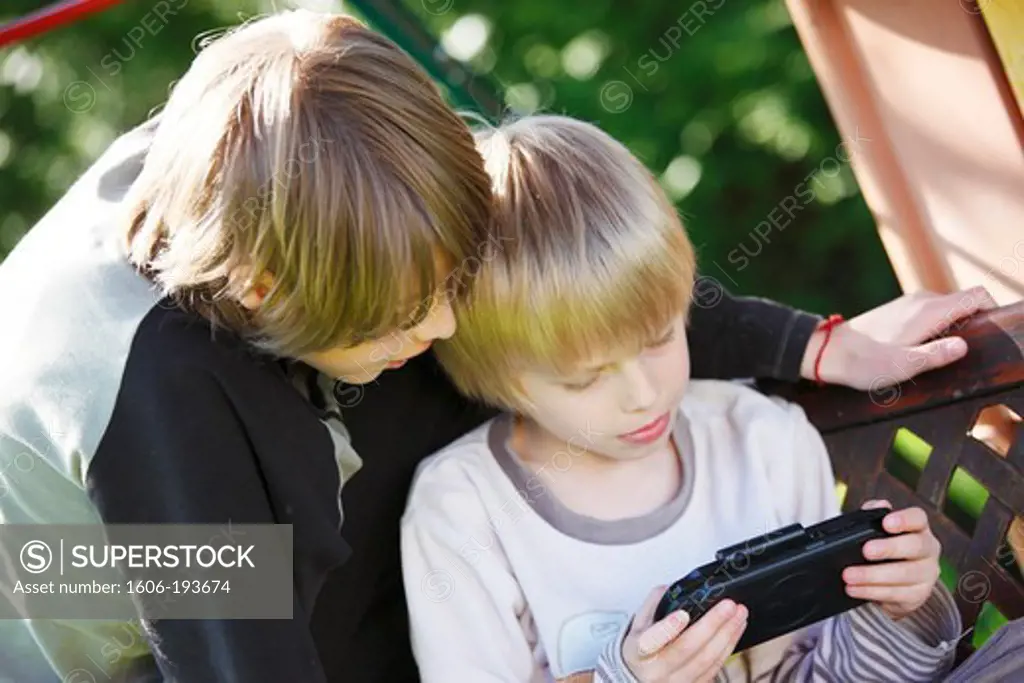 France, Boys, 8 And 11 Years Old, Playing In The Garden With A Games Console