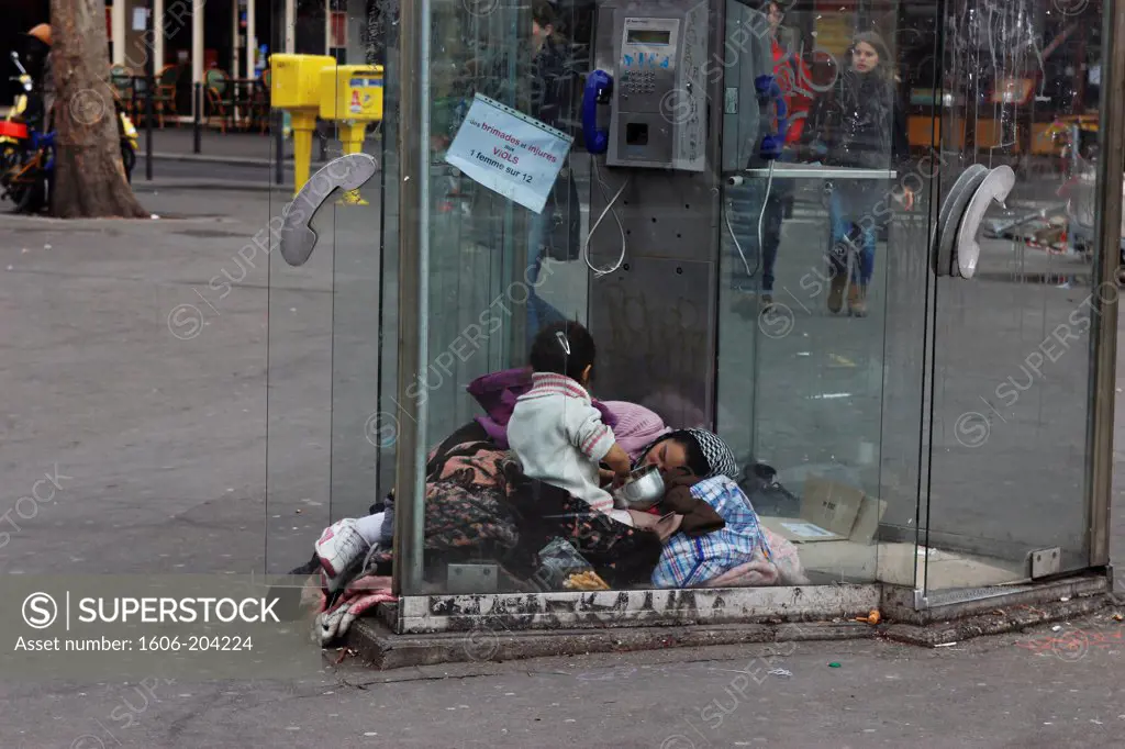 FRANCE, Paris, 11th arr, Place de la Bastille, Romanian mother and her daughter living in a public phone box, winter