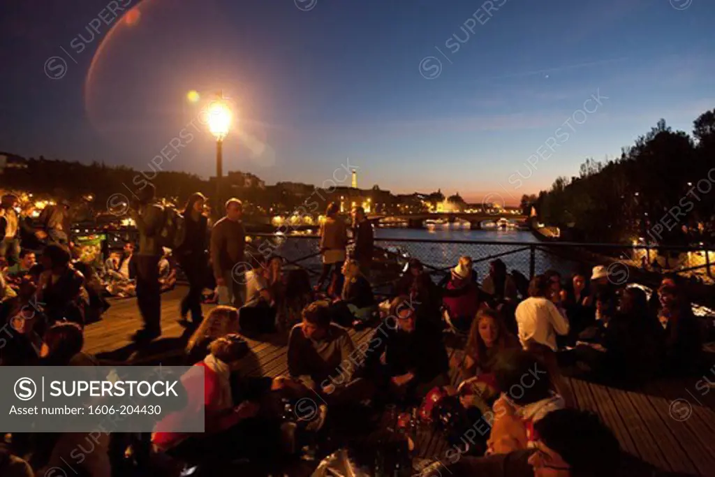 France. Paris. 1st district. Pont des Arts, Groups of people gathered for outdoor meal at dusk