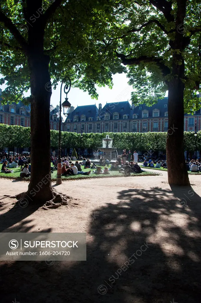 France, Paris, 3rd-4th districts, Place des Vosges, People gathered on the lawn