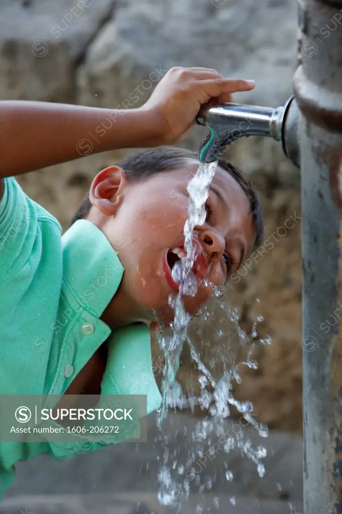 Boy drinking from a fountain Italy.