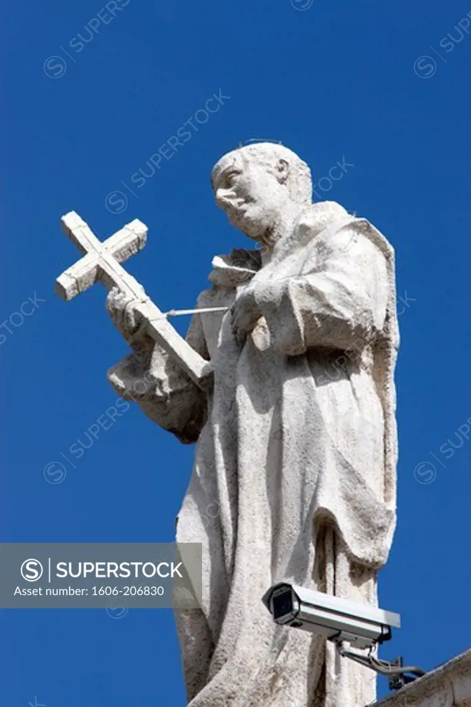 Italy. Rome. The Vatican. St. Peter's Square. Focus on the statue of a saint above the colonnades. Surveillance camera.