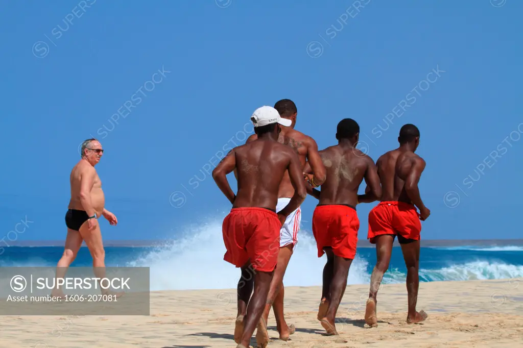 Western Africa,Republic of Cape Verde, Sal island. Santa Maria. Local people running on the beach.
