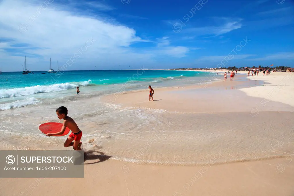 Western Africa,Republic of Cape Verde, Sal island. Santa Maria. Kid playing skim board on the beach.