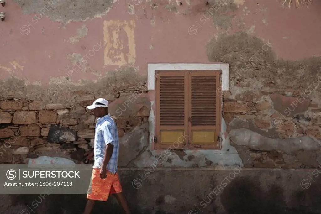 Western Africa,Republic of Cape Verde, Sal island. Santa Maria.Passer-by in front of an used wall.