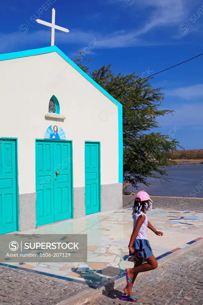 Western Africa,Republic of Cape Verde. Sal Island. Palmeira. Girl playing in front of a colored church.