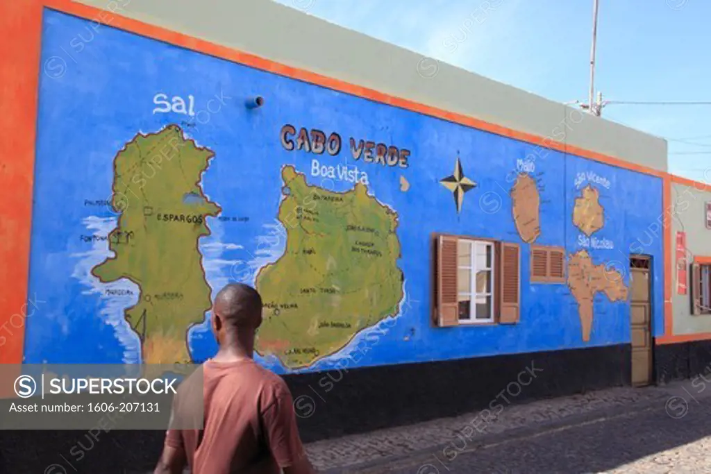 Western Africa,Republic of Cape Verde. Sal Island. Palmeira. Man walking before a painted map on a wall.