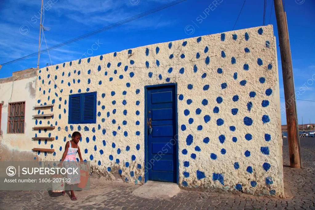 Western Africa,Republic of Cape Verde. Sal Island. Palmeira. Girl walking before a colored house.