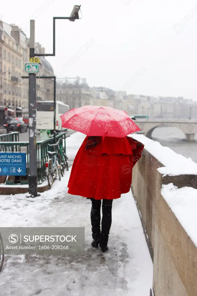 FRANCE, Paris, pedestrian with red umbrella walking quai Saint-Michel in the snow