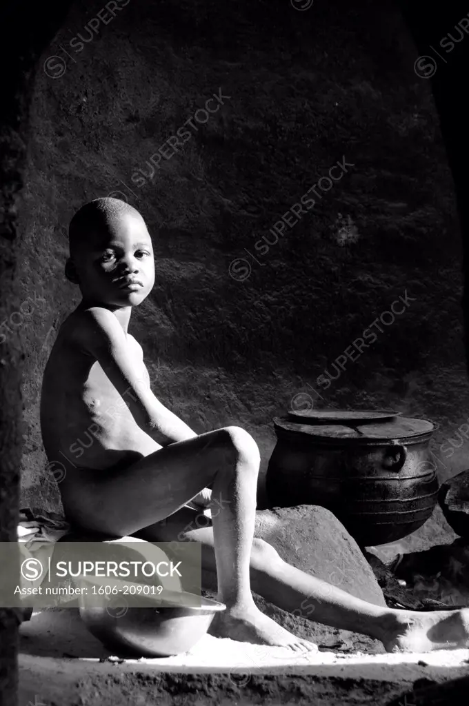 TOGO Tamberma country a young naked boy is sitting in a recess used as a kitchen