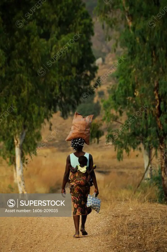 TOGO a woman is carrying her baby against her back and a bag on her head
