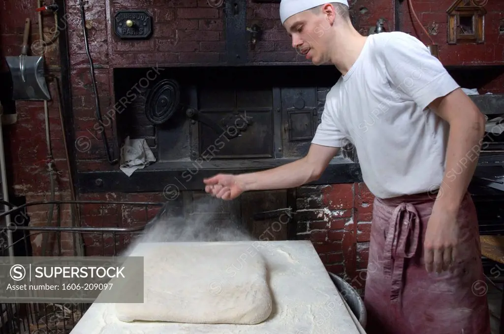 France, Paris, bakery, a baker throws flour on bread dough