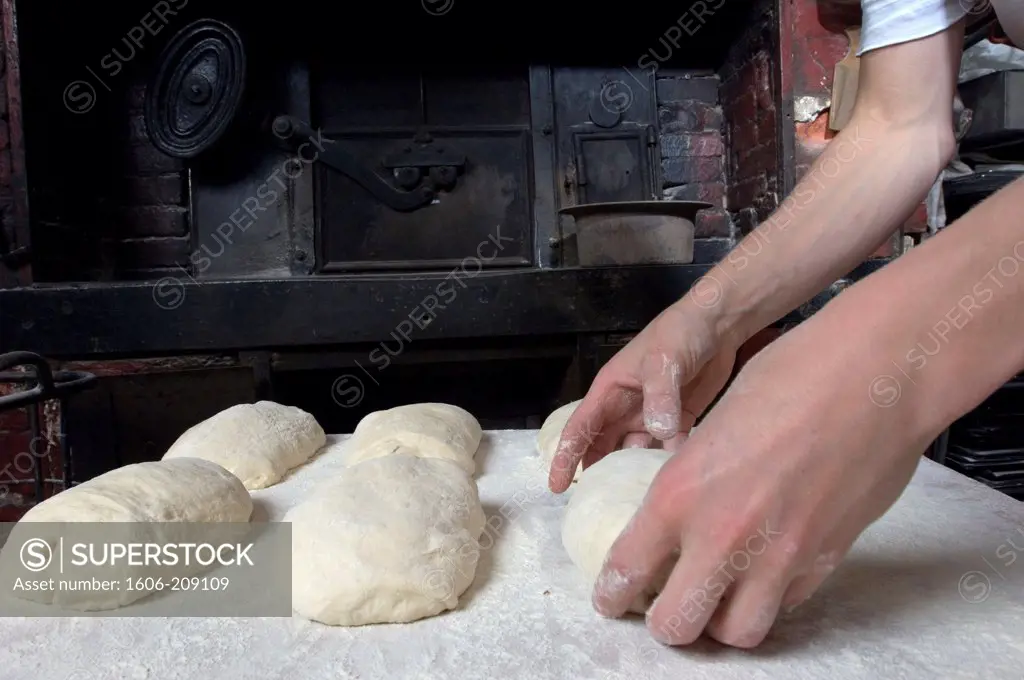 France, Paris, bakery, a baker puts bread dough on a worktop