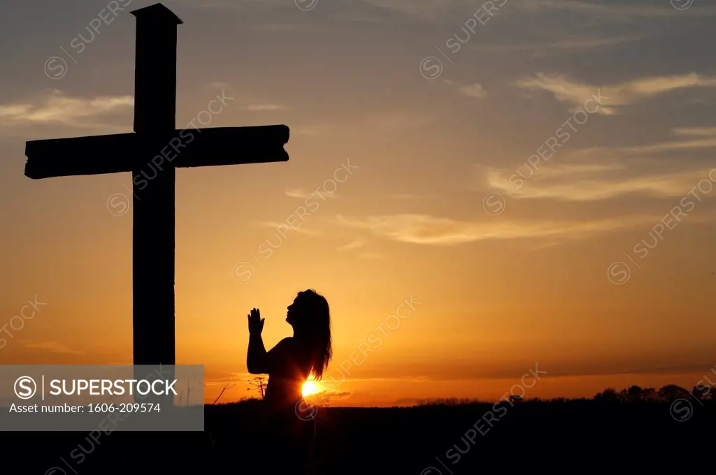 Woman praying at sunset. France.