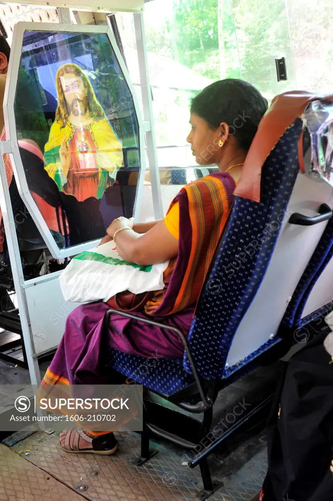 Woman sitting in a public bus in front of Jesus Chist image poster in Tamil Nadu,South India,Asia