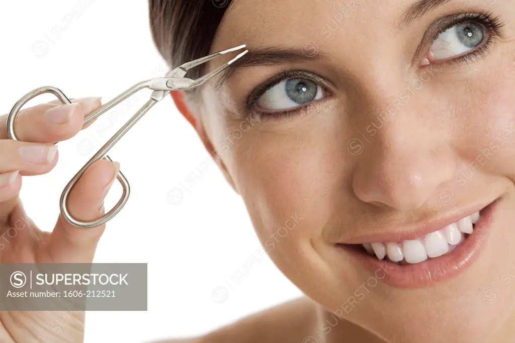 Close-up of a smiling young woman using tweezers, looking up.