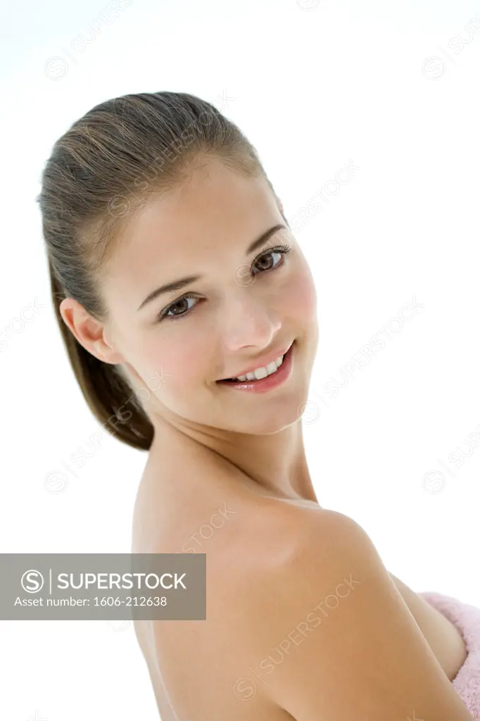 Beauty portrait of a young woman wearing a bath towel, smiling and looking at camera