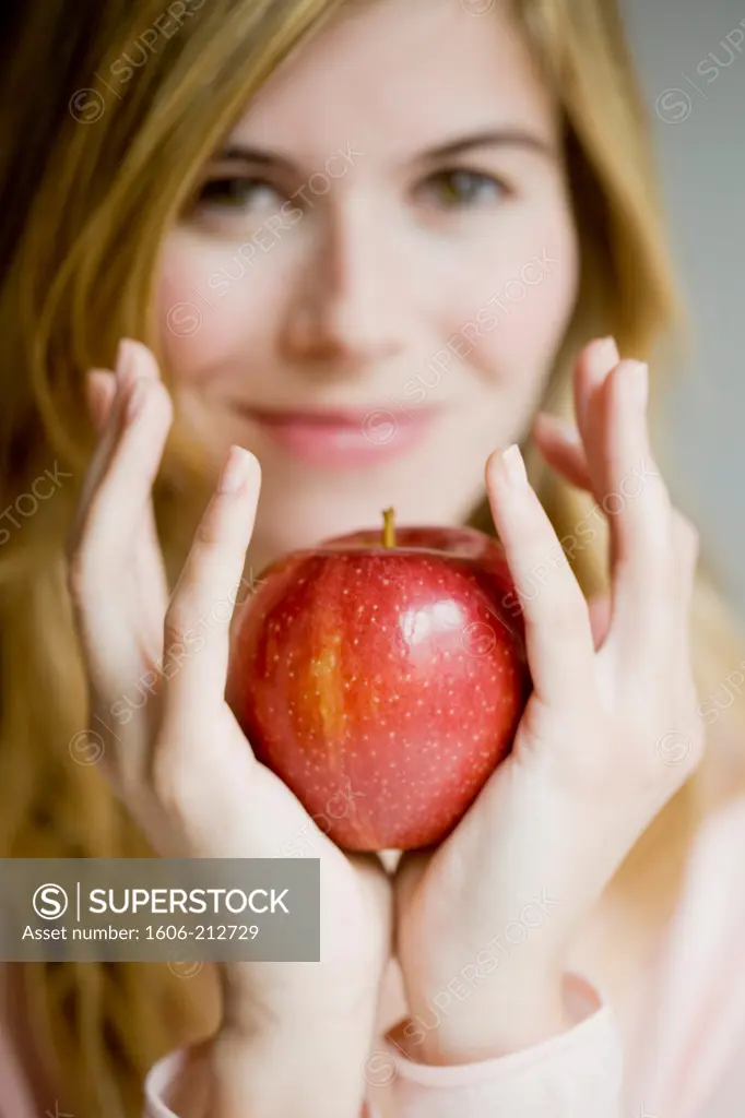 Close-up of a young woman holding a red apple in her hand