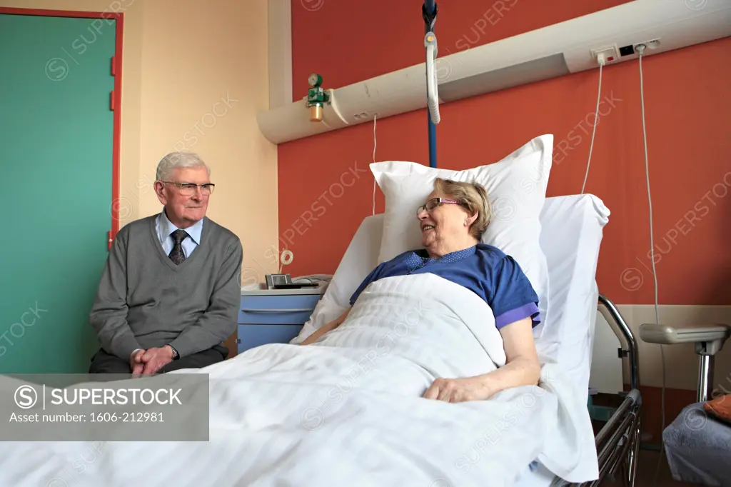 France, senior couple at hospital speaking together.