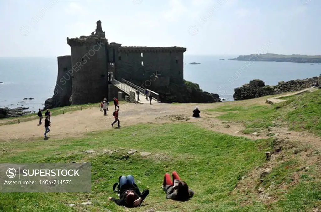 France, Vendée, Yeu island, Old Castle on the wild coast (14th century), visitors sitting in the foreground.