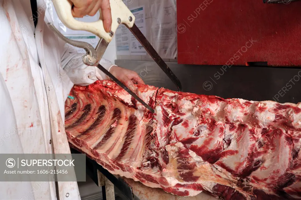 France, Paris, a butcher carves the ribs of a beef with a saw