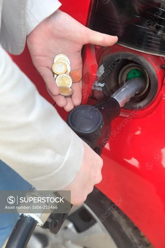 France, woman fills up her car with petrol with coins in her hand.