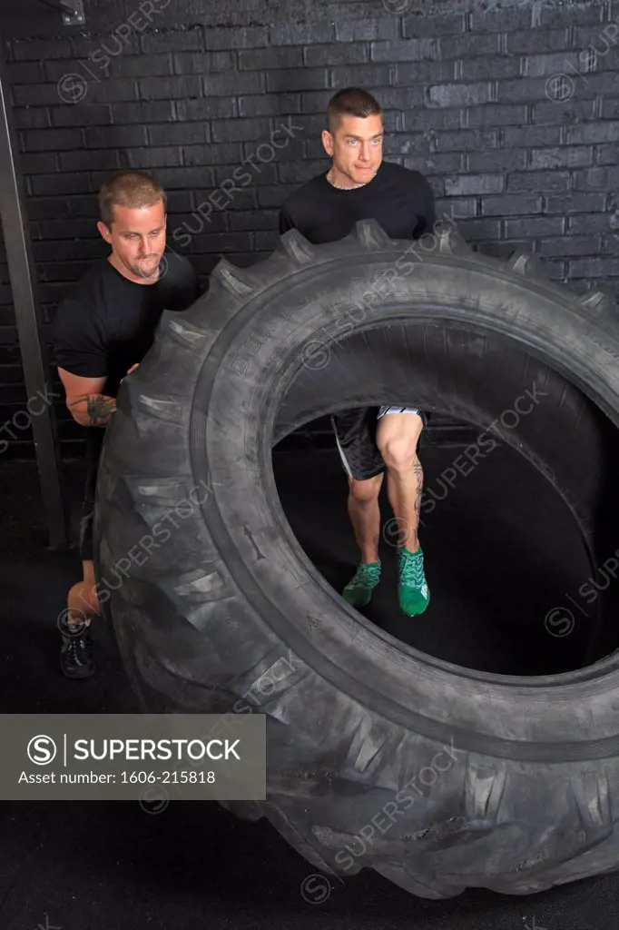 France, two men moving a wheel in a crossfit gymnasium..