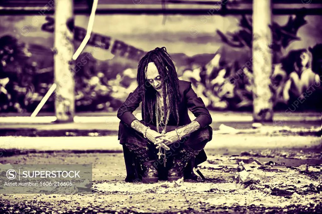 DeathWorker, a Cyberpunk man sitting in an empty factory