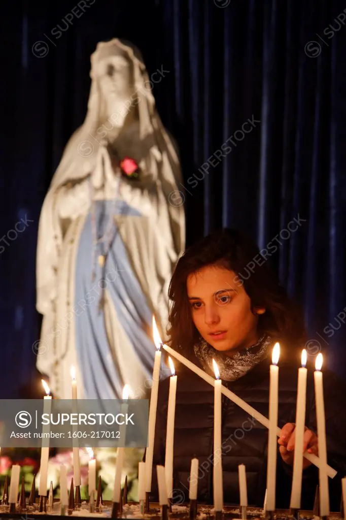 Teenager lighting a candle in La Madeleine church. Paris. France.