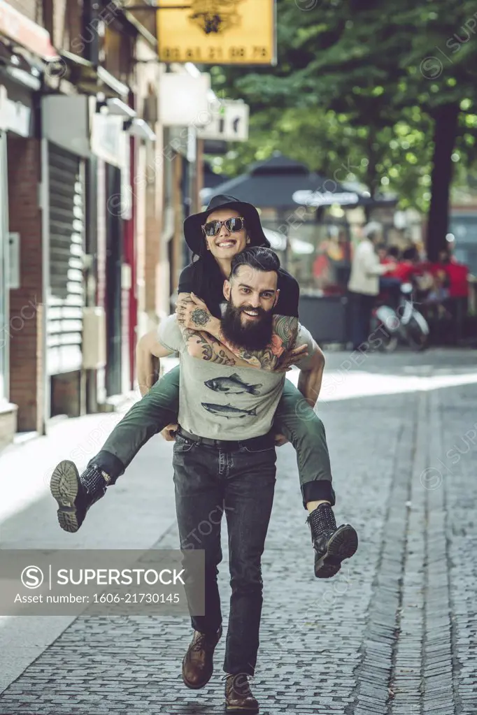 Young man carrying his girlfriend on his back in an urban environment