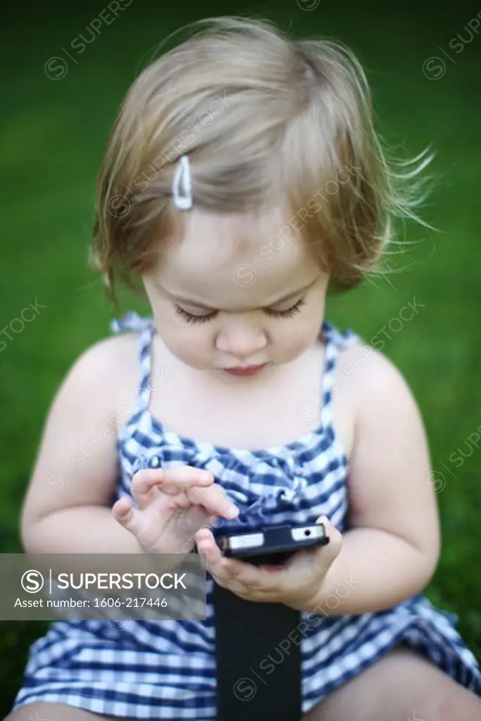 A little girl playing with a cell phone