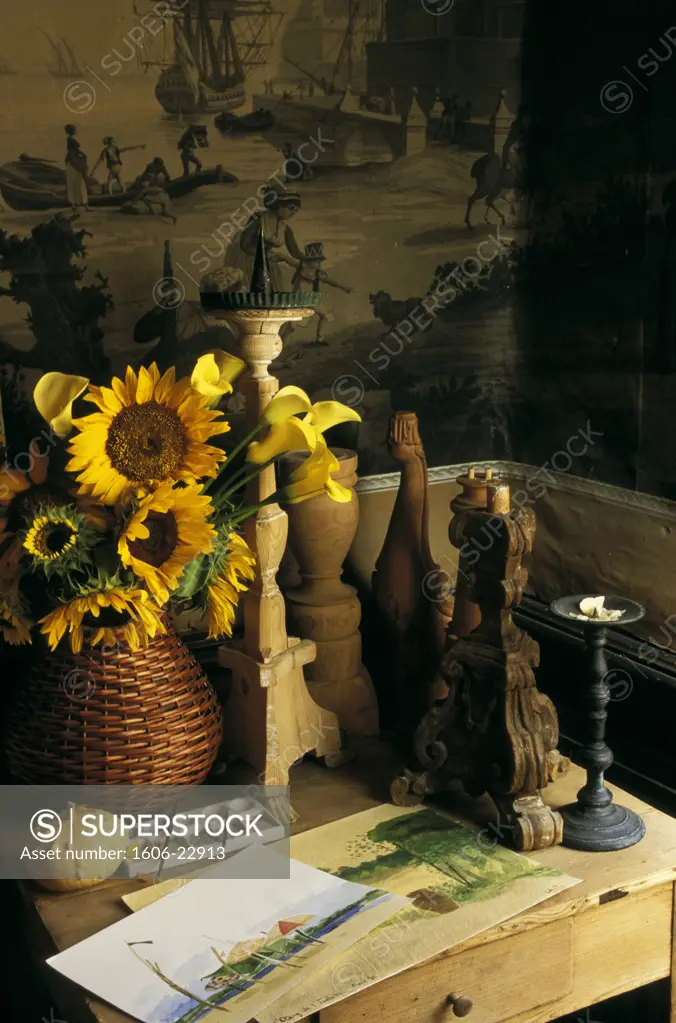 13. Noves, intérieur salon ancien, gros plan sur bougeoirs en bois, aquarelles et bouquet de tournesols sur petite table, dessin au mur