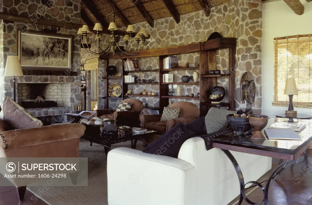 Afrique du Sud, intérieur Clearwater Kudu Lodges, salon, canapés et fauteuils, bibelots sur étagères, cheminée, murs en pierre