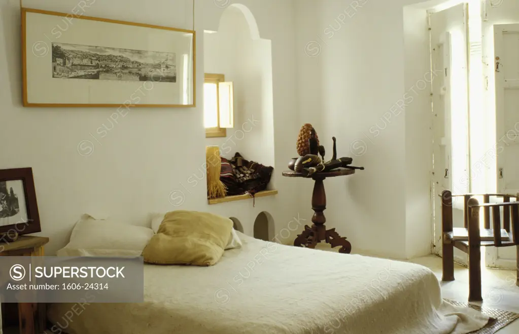 Ibiza, 1065 Casa Victor, intérieur chambre, objets ethniques sur table et rebord de fenêtre, gravure au dessus du lit, murs blancs